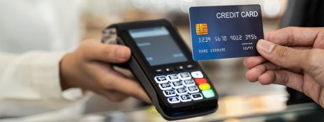 Person using IndusInd Bank credit card at a terminal, highlighting the importance of regular use to keep accounts active and avoid closure.