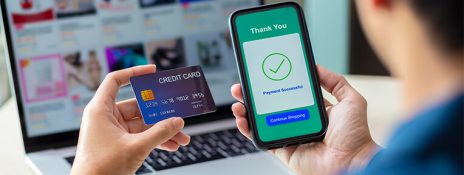 Person holds credit card and phone showing payment success, highlighting balance transfers' effect on credit score. Apply for IndusInd Bank Credit Card for seamless banking