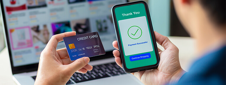 Person holds credit card and phone showing payment success, highlighting balance transfers' effect on credit score. Apply for IndusInd Bank Credit Card for seamless banking