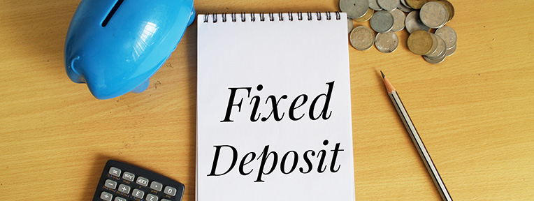 Notepad with Fixed Deposit, calculator, and coins, symbolizing how to calculate monthly interest on ₹1 lakh FD with IndusInd Bank.