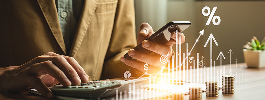 A person uses a smartphone and calculator with coins and financial icons, symbolizing how IndusInd Bank offers secured credit with Credit Card against FD.