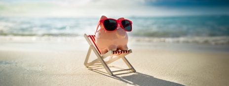 Piggy bank on beach symbolizing smart savings for travel by securing competitve interest rates for travel loan with IndusInd Bank.