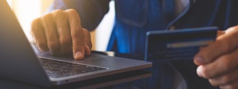 Person using laptop holding a credit card. Learn how to apply online for a credit card and choose IndusInd bank for easy application.