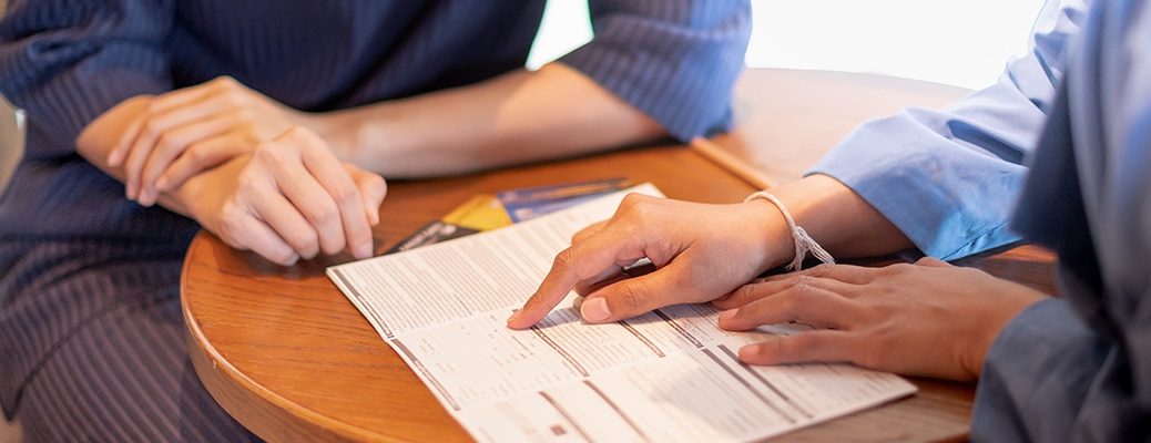 Two people review a brochure on IndusInd Club Vistara Explorer Credit Card perks, highlighting travel benefits and rewards.