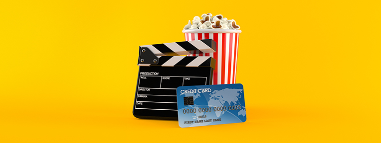 Popcorn, clapboard, and credit card on yellow background signifying Savings and offers on movie tickets available IndusInd Bank Credit Card.