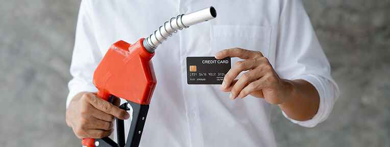 Man holding fuel nozzle and indusind bank credit card, ideal for maximising savings and managing fuel expense.