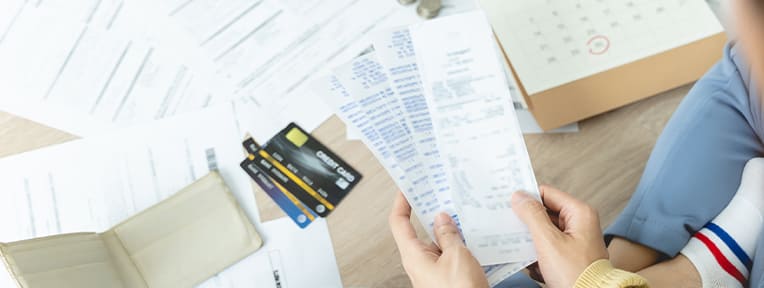 Person reviews receipts for credit card refunds. Use IndusInd Bank cards for a smooth refund process and enticing benefits.