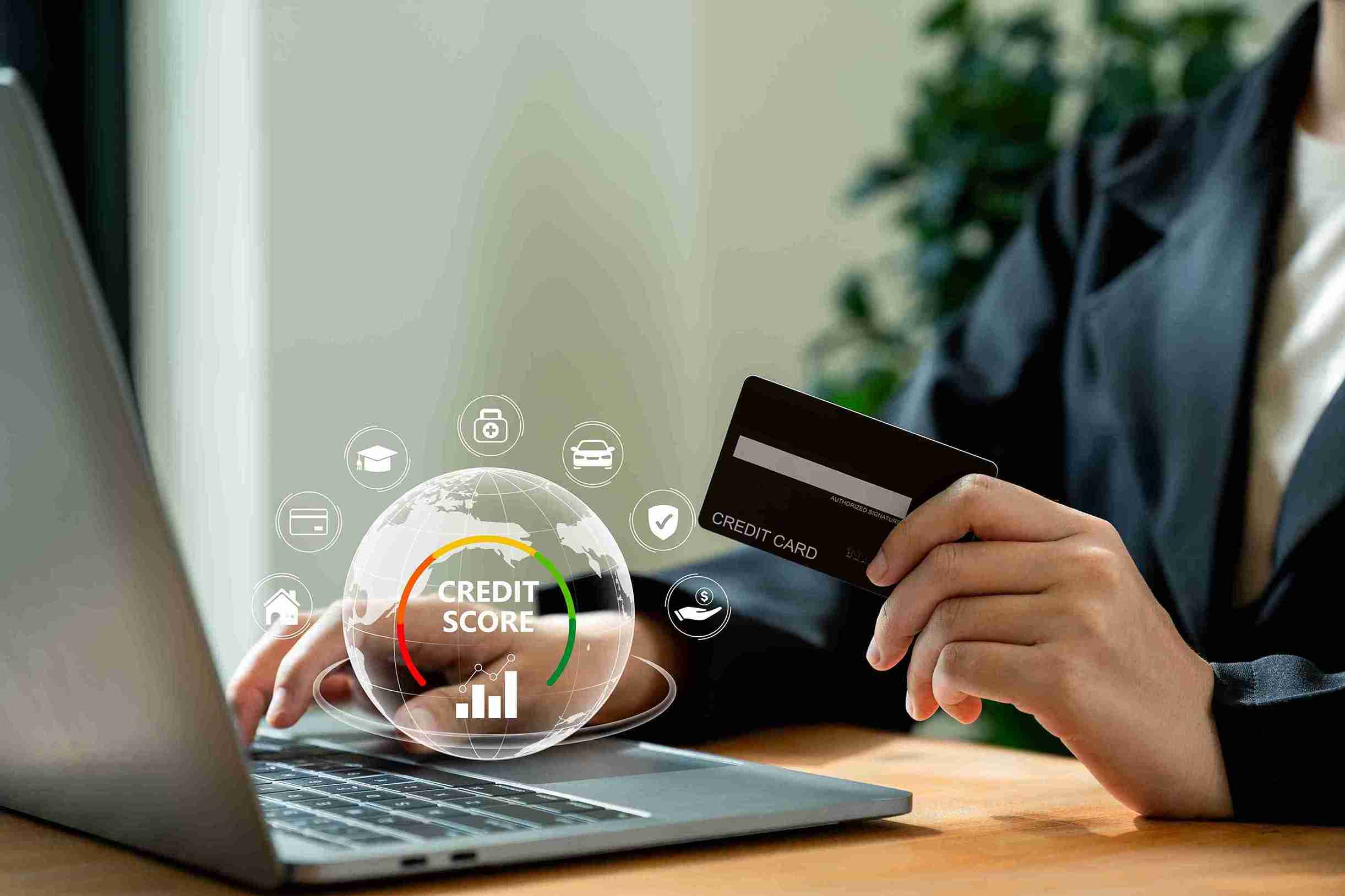 Person with IndusInd Bank credit card and laptop, highlighting how secured cards can help improve credit scores and achieve financial goals.