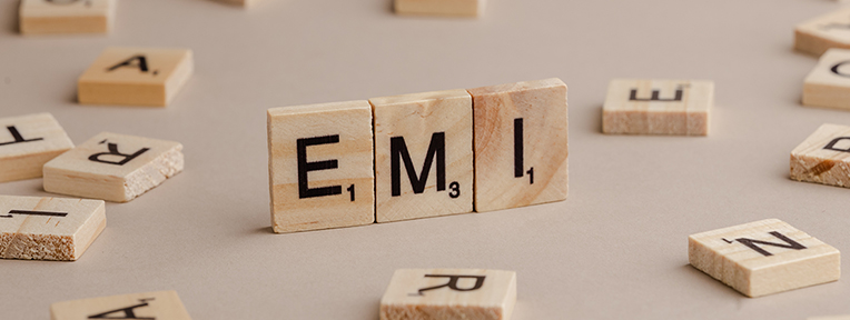 "EMI" spelled in wooden tiles, representing IndusInd Bank's Credit Card easy monthly installments.