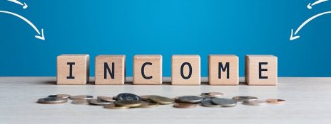 Wooden blocks spelling 'INCOME' above coins signifying minimum income for personal loans. Explore IndusInd Bank Personal Loan for options.