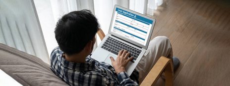A person is using a laptop, applying to IndusInd Bank Personal loan form easily and with convenience to secure their future.