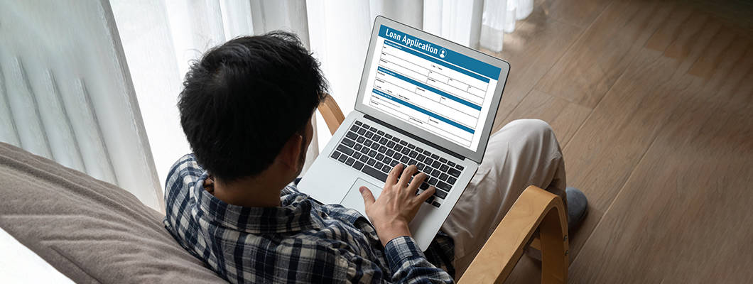 A person is using a laptop, applying to IndusInd Bank Personal loan form easily and with convenience to secure their future.