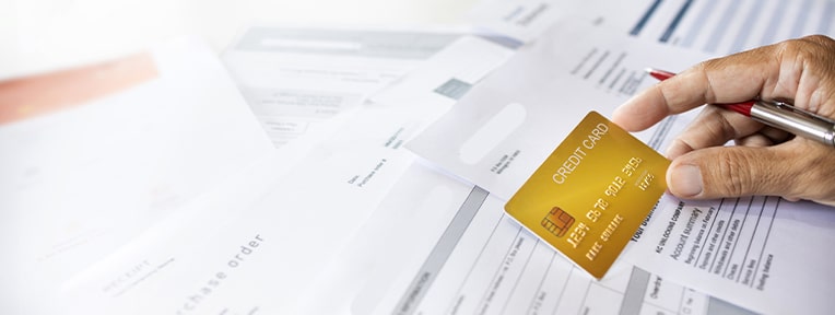 A person holding a credit card over application documents, symbolizing the process of applying for a secured credit card with IndusInd Bank to build credit easily.
