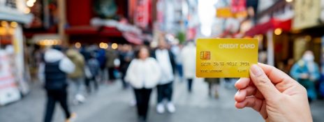 Personal holding IndusInd Bank Forex Card on a busy foreign street highlighting travel ease and money management.