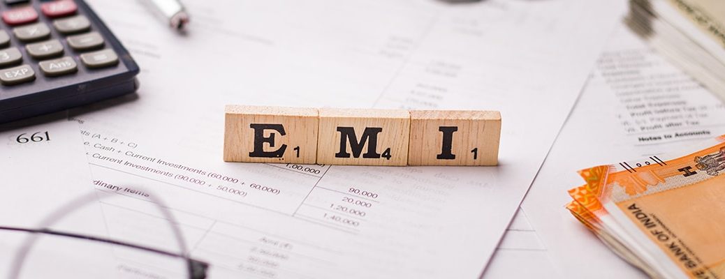 Wooden blocks spelling 'EMI' on financial papers and calculator, promoting smart EMI management with IndusInd Bank credit cards.