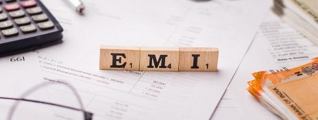 Wooden blocks spelling 'EMI' on financial papers and calculator, promoting smart EMI management with IndusInd Bank credit cards.